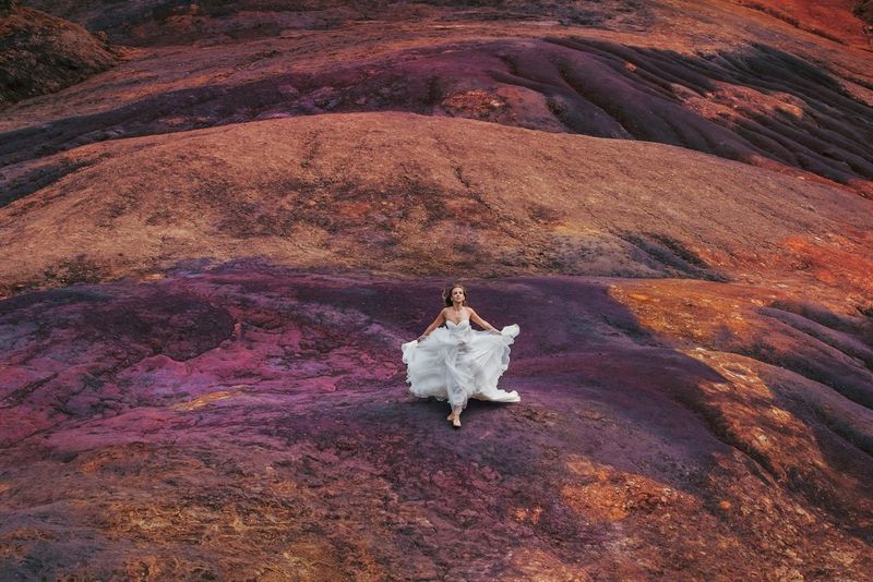 A woman in a white dress runs across purple and orange volcanic rock on the island of Mauritius. Photo taken by Katya Mukhina on a Canon EOS-1D X.