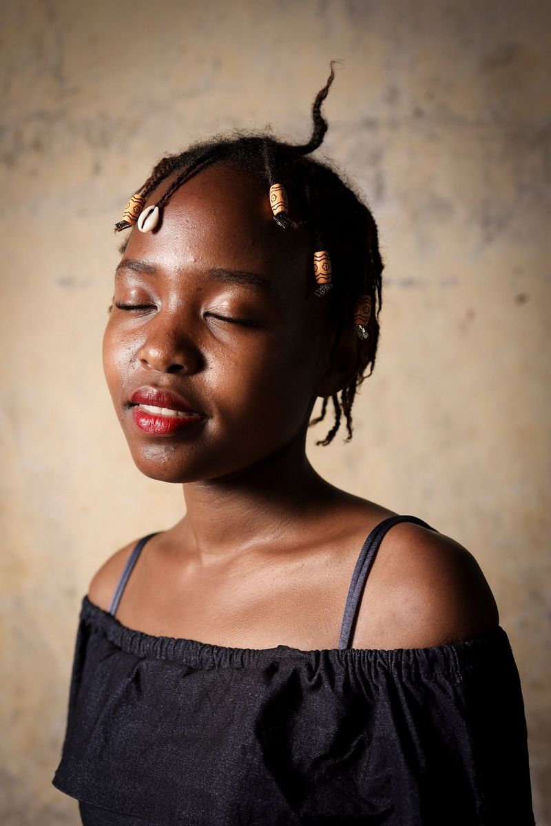 A young Kenyan woman poses with her eyes closed in front of the camera, taken by Lieve Blancquaert on a Canon EOS R.
