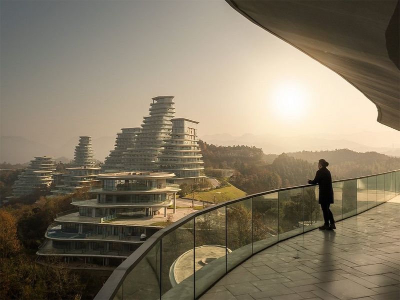 A woman stands on a balcony overlooking tall, rounded glass towers. Photo by Fernando Guerra with a Canon TS-E 24mm f/3.5L II lens.