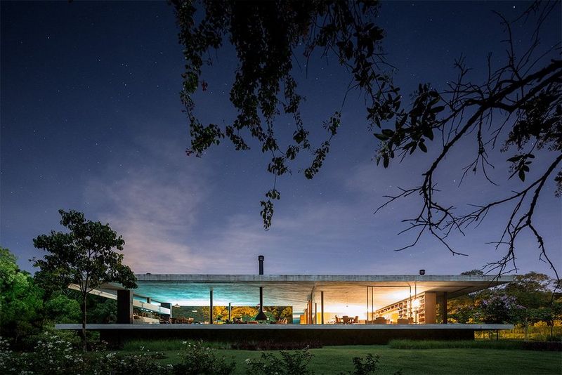 A large one-storey glass-fronted house is seen from the garden, beneath a deep blue twilight sky. Photo by Fernando Guerra with a Canon TS-E 17mm f/4L lens.