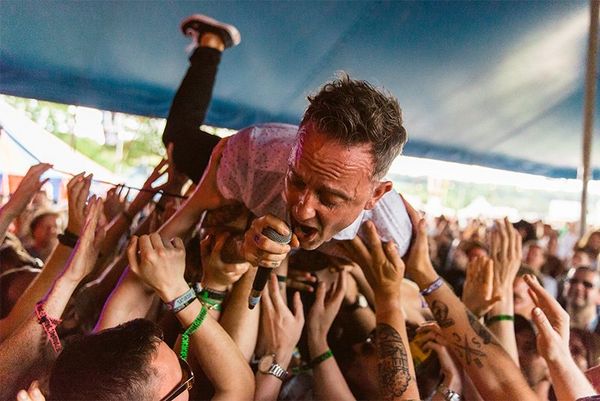 A singer crowdsurfs in a tent, mic in hand. Photo by Ben Morse.
