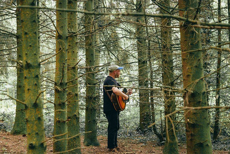 A guitarist practices among some trees. Photo by Ben Morse.