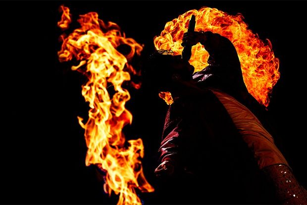 A singer’s silhouette is seen in front of a large flame. Photo by Bart Heemskerk.