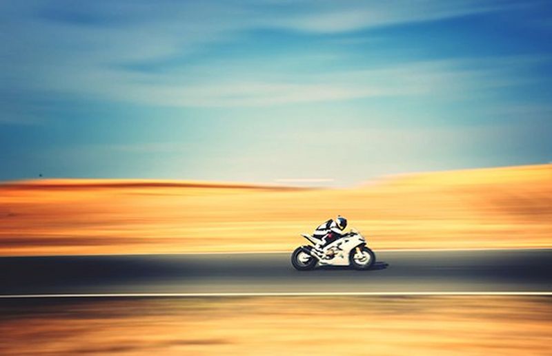 A motorbike riding through a blurred desert landscape.