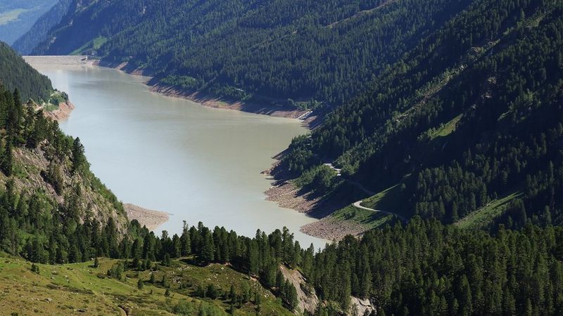 A lake surrounded by mountains covered with trees.