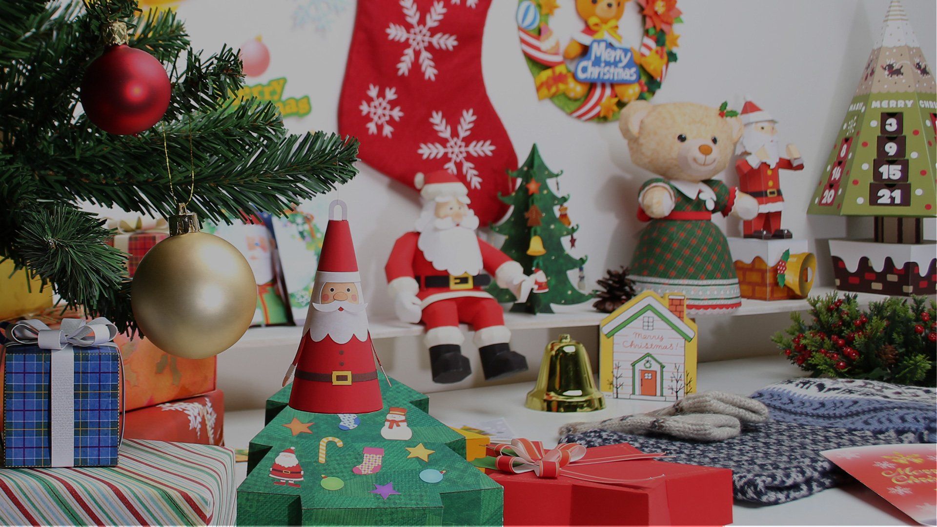 A table is filled with Christmas-themed paper crafted decorations and gifts.