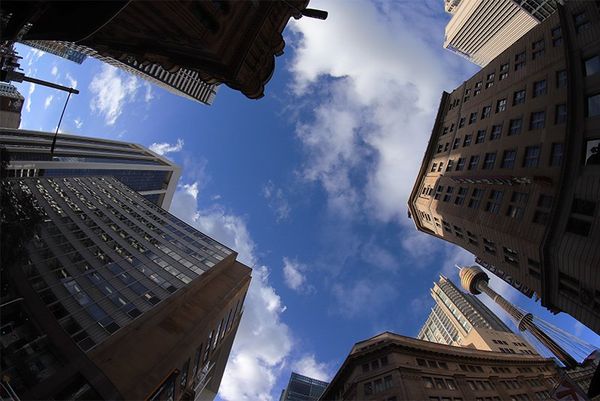 A view looking up at a blue sky, with tall buildings on all sides.