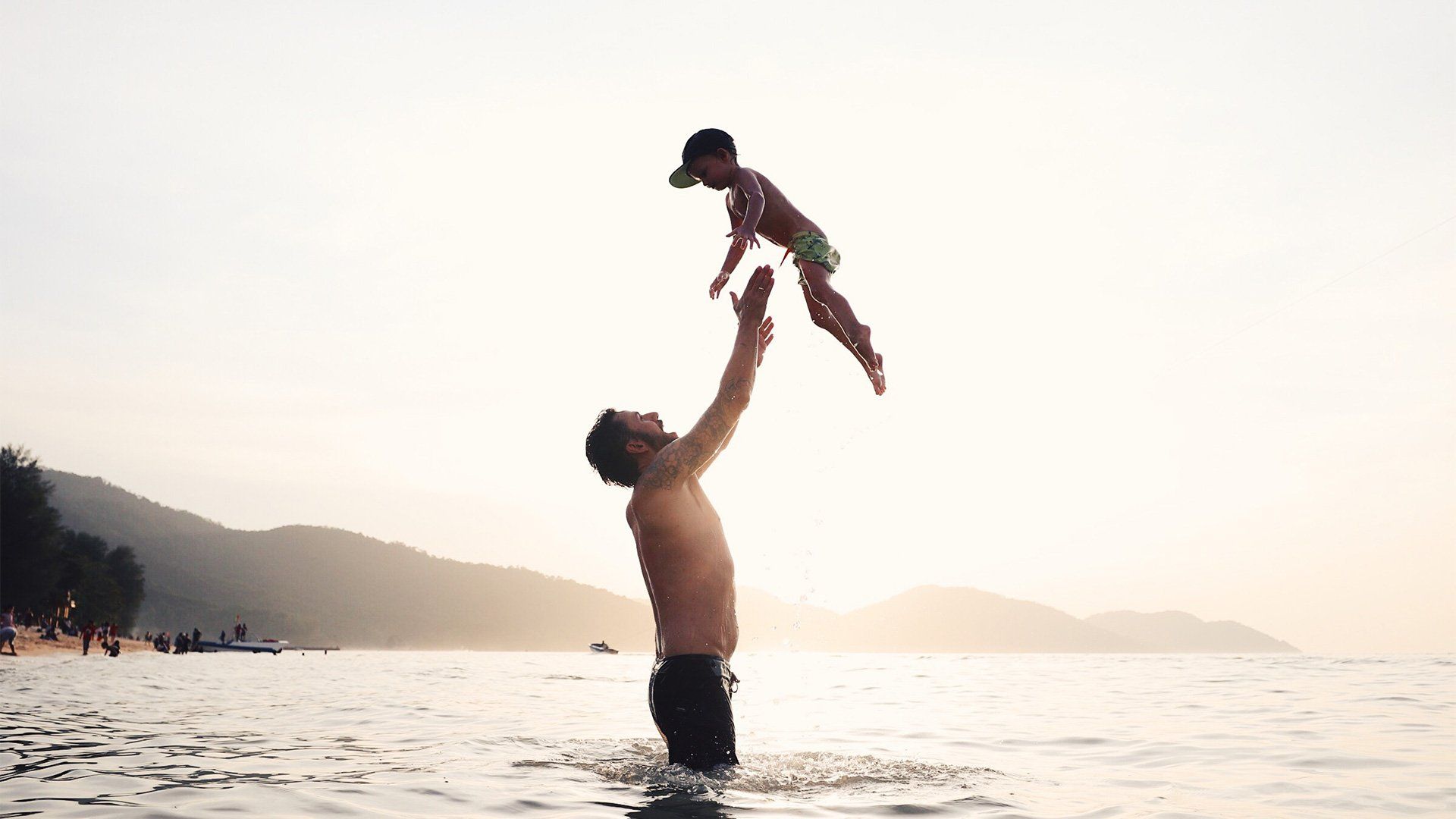 A man stands in the sea and throws his son in the air. Photo by Christian Anderl.