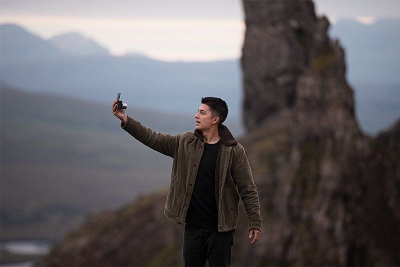 YouTube star and vlogger Mike Gray stands in a mountainous landscape filming himself with a Canon PowerShot G7 X Mark III.