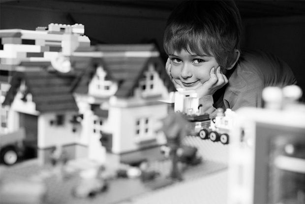 A smiling boy with a Lego play set.