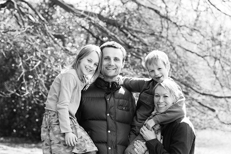 A family group posing in front of a tree.