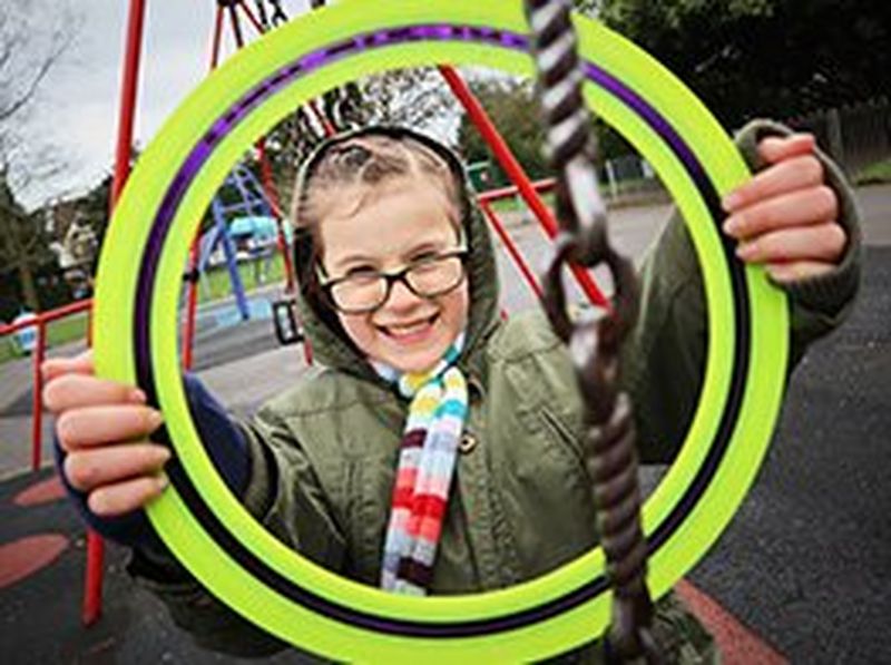 A girl holds a frisbee in front of her like a picture frame around her face.
