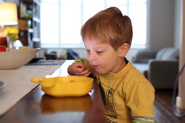 A boy looks into a yellow bowl on the table in front of him. Taken on a Canon EOS M50 by Katja Gaskell.