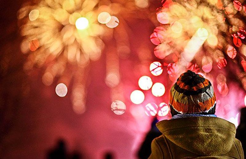 A child watches bright pink fireworks.