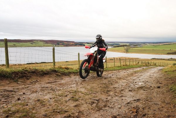 A sharp shot of a rider on a dirt-bike in motion, the background and rider in focus.