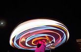 A long exposure of a Ferris wheel creates concentric circular streaks of coloured light.