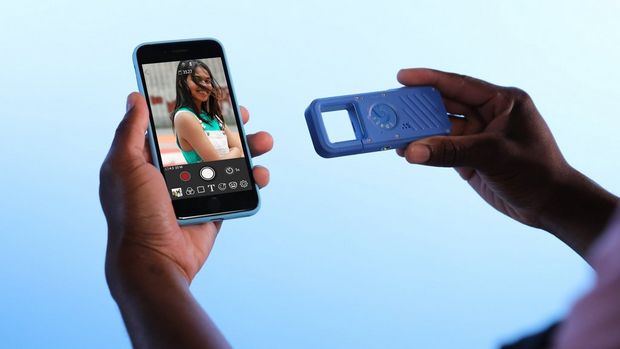 A blue Canon IVY REC being used with the Canon Mini Cam app on a smartphone, displaying a photo on its screen.