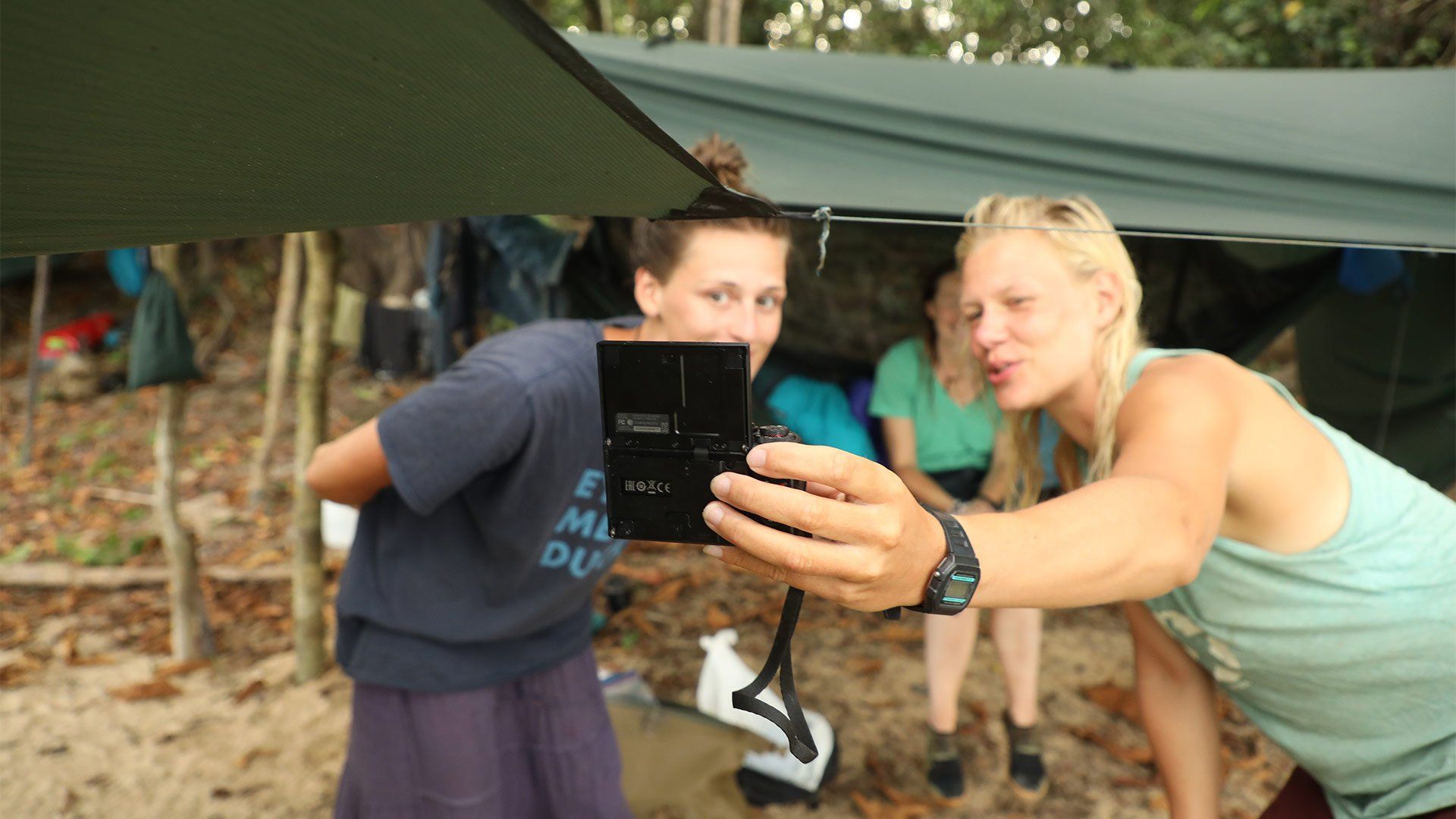 Laura and Ness Knight use a Canon PowerShot G7 X Mark II to film themselves in front of a tent in the jungle, inside which Pip Stewart is sitting.