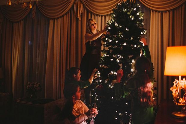 Three kids and their mother decorate a Christmas tree.