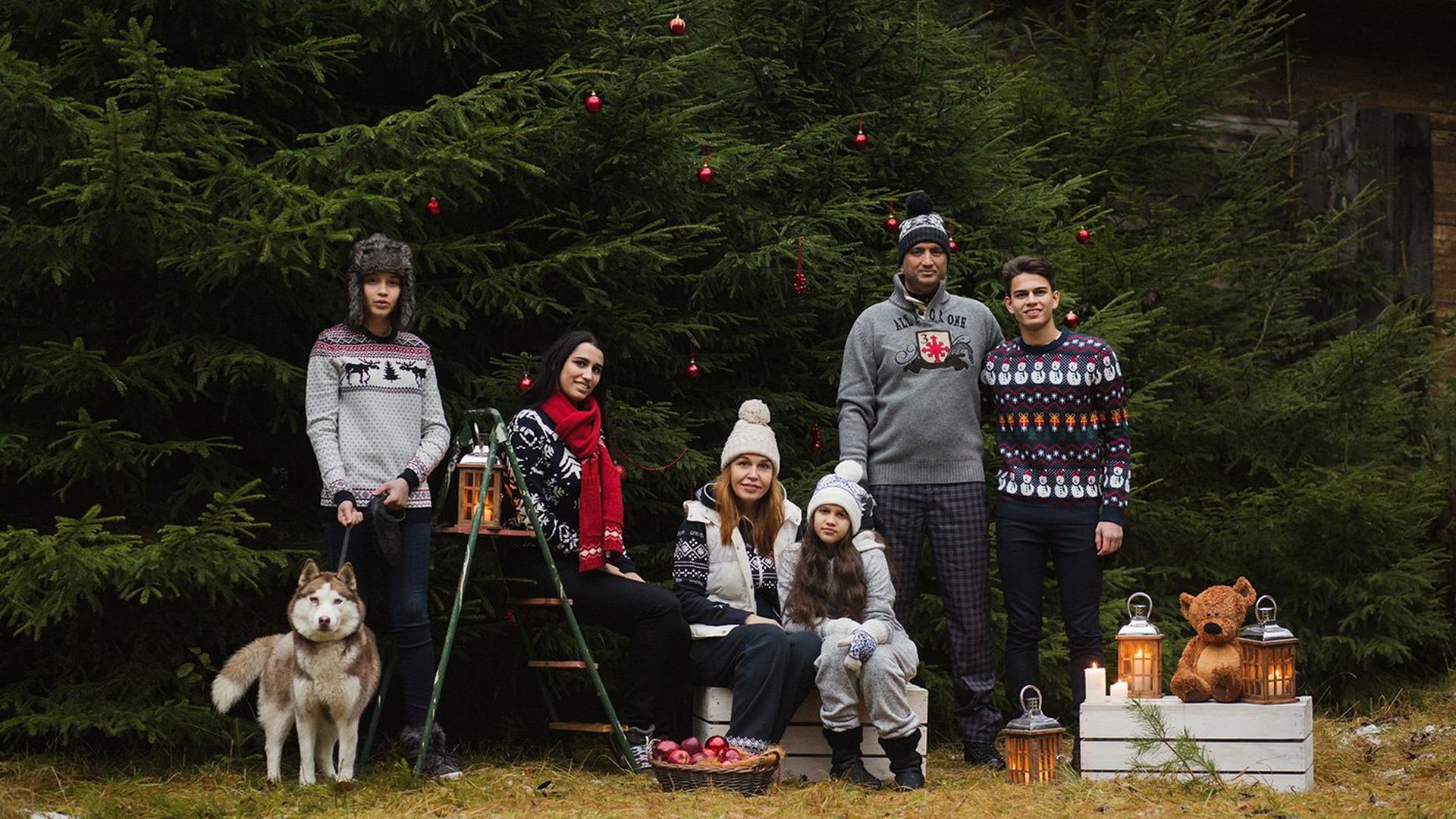 A family of six stands outside in sweaters.