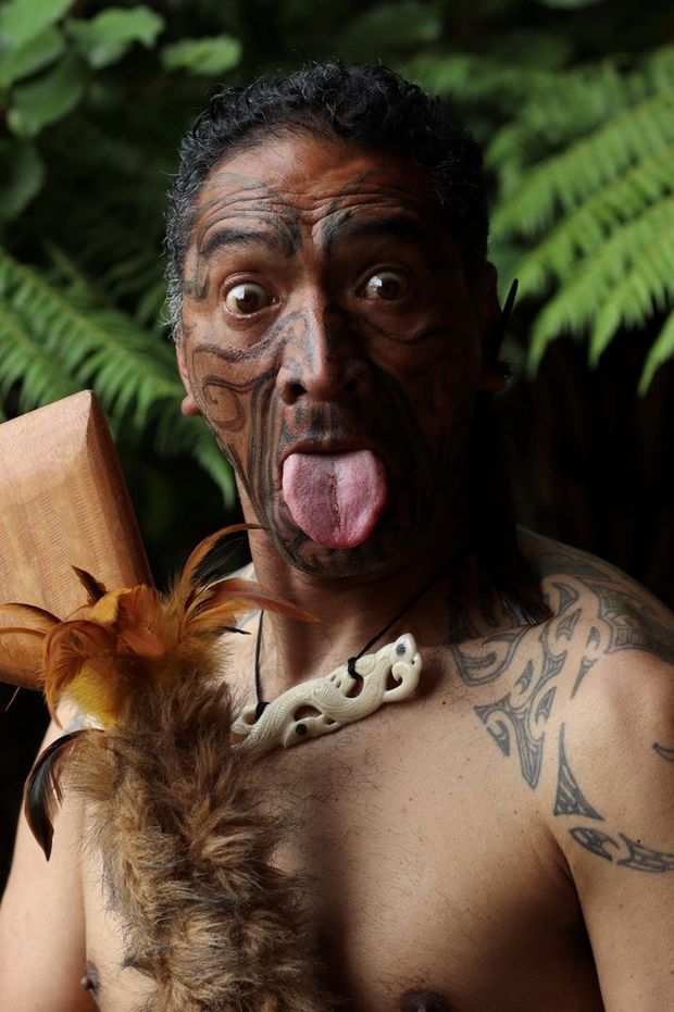 A portrait of a man in traditional Māori dress performing the Haka.