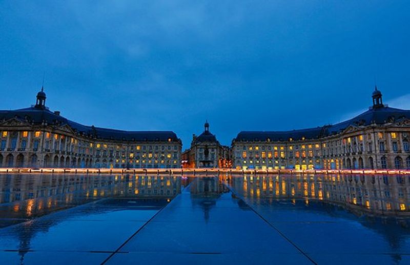 Pink fireworks explode over a bridge at night.