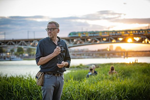 Photographer Piotr Malecki stands in long grass holding a Canon EOS M6 Mark II beside the river Vistula.