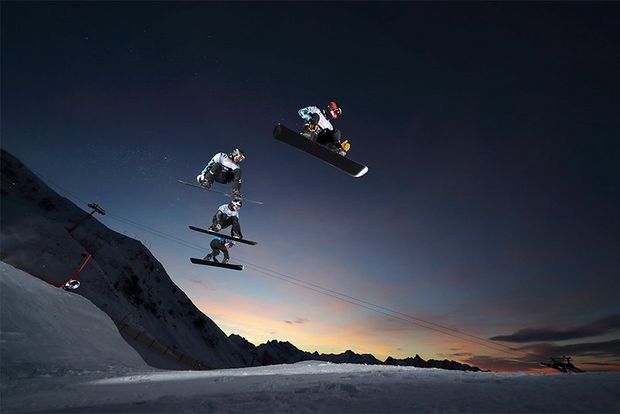 Three skiers captured in mid-air against a sunset sky.