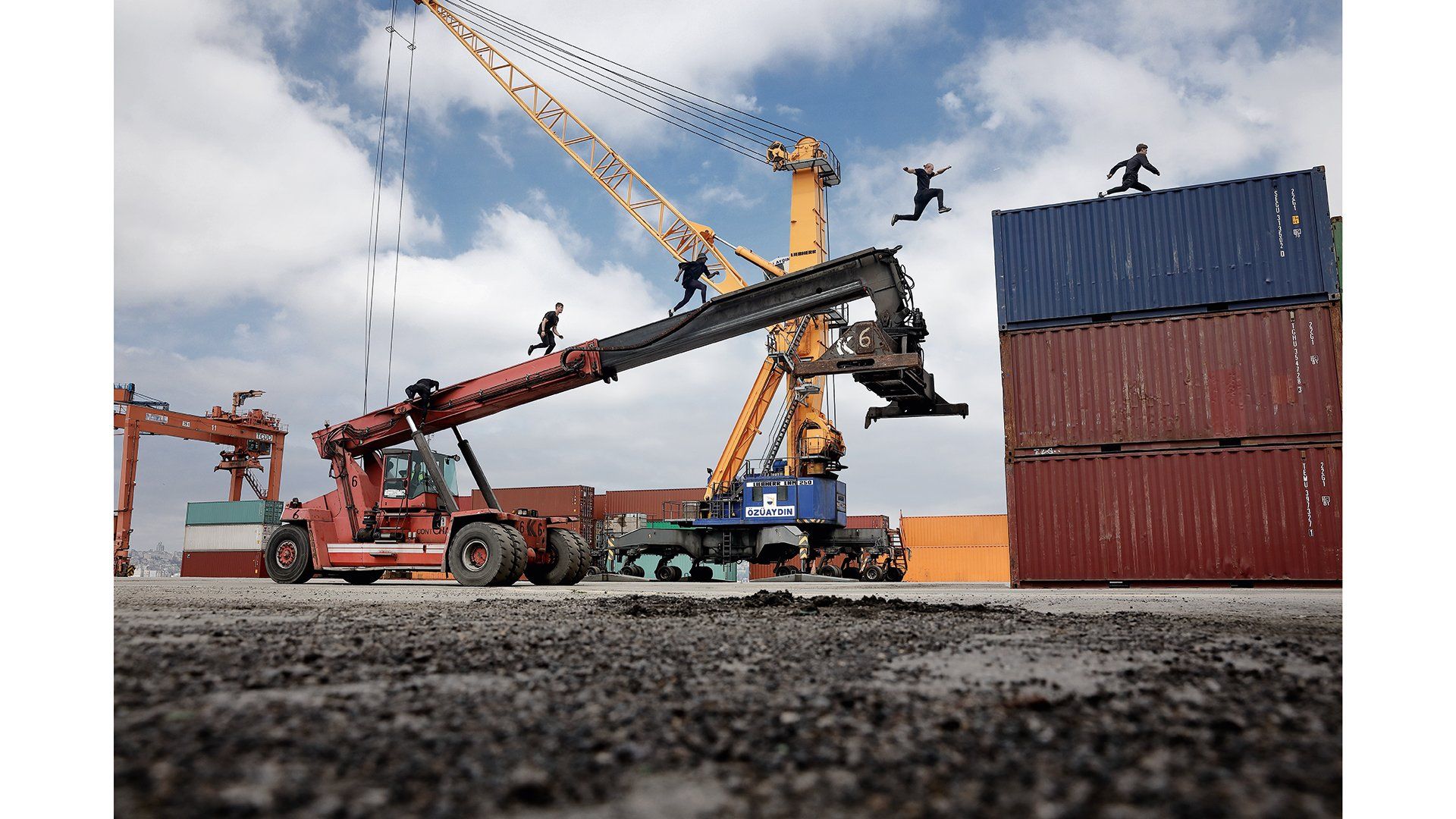 4 men running up a crane on to shipping containers