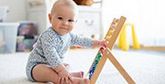 A baby sits with an abacus.