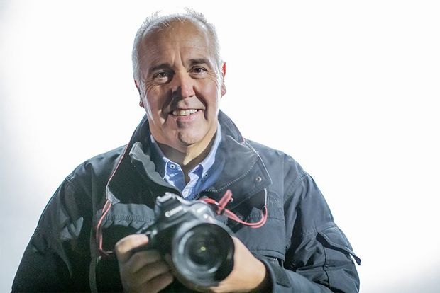 Sports photographer Dave Rogers holding a Canon camera.
