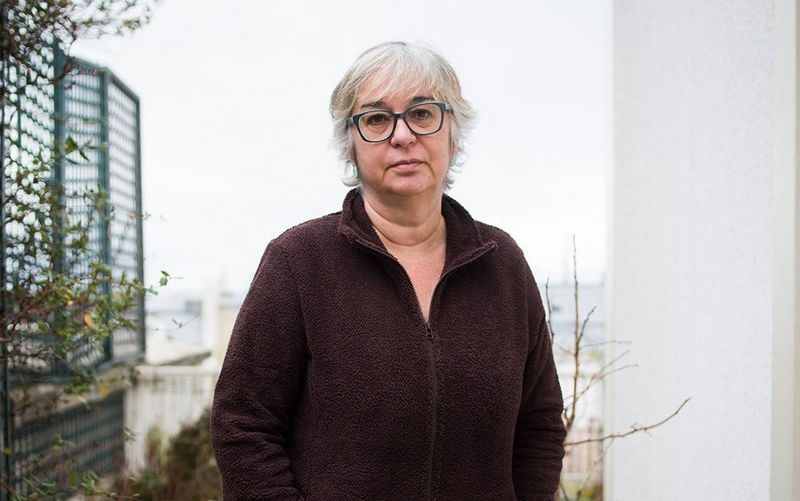 Ayperi Karabuda Ecer stands in a courtyard garden, looking at the camera.