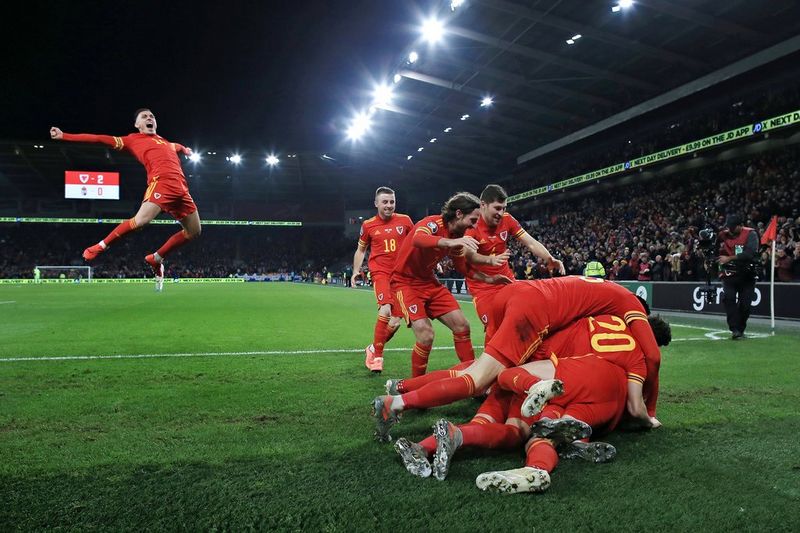 Football players from the Wales team celebrating their win over Hungary by bundling on the field. 