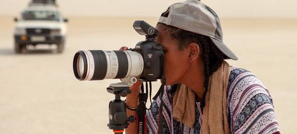 Canon Ambassador Aïda Muluneh looks through the lens of a Canon EOS 5D Mark IV on a tripod. 