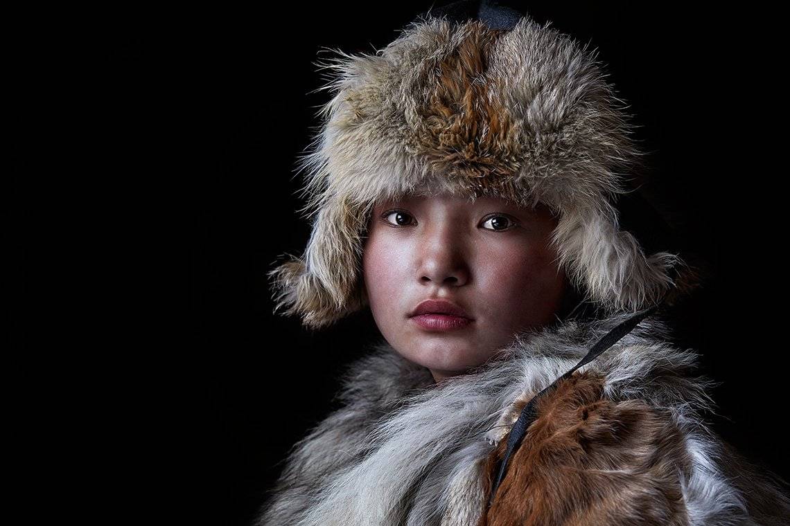 A young Kazakh girl wearing traditional fur coat and hat