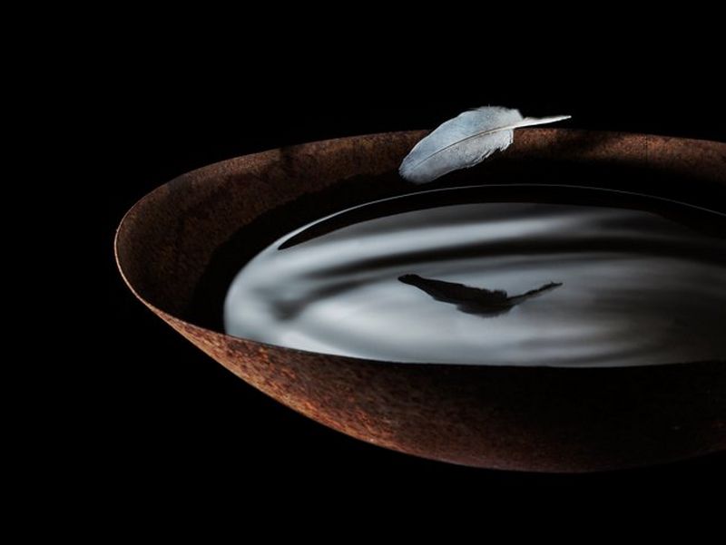 A feather hovers above a wok full of liquid, photographed by Eberhard Schuy on a Canon EOS 5D Mark II.
