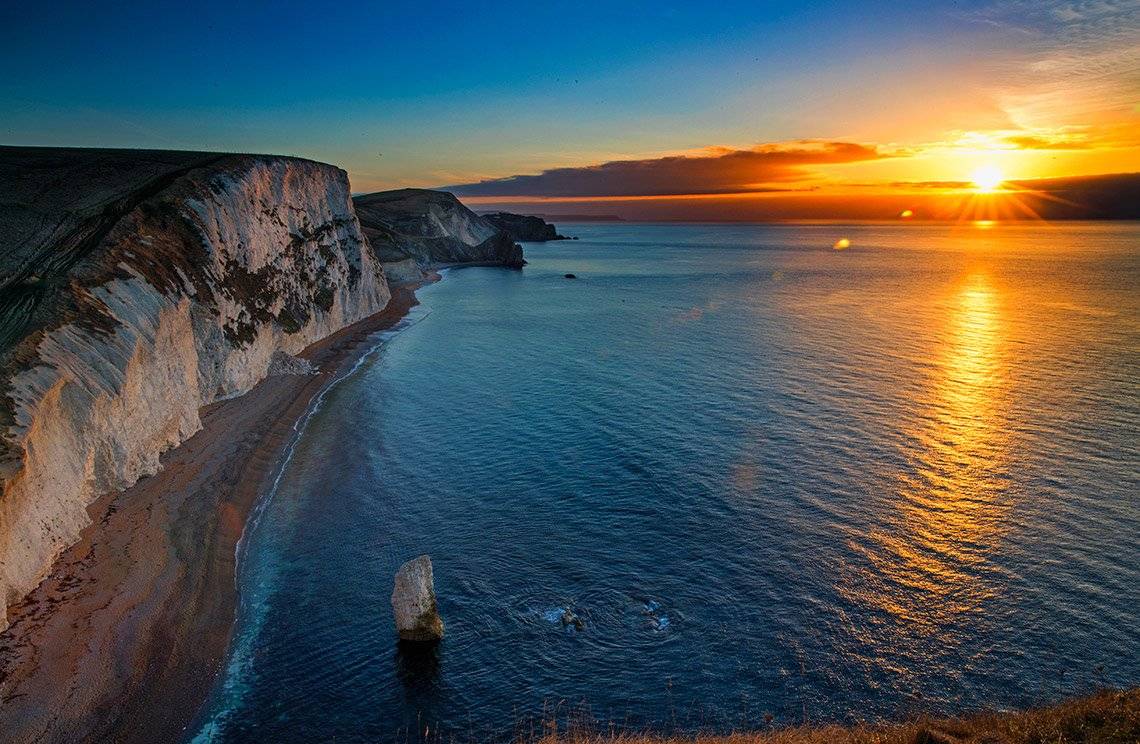 The sun setting over sea, lighting up white cliffs, photographed by Marc Aspland on a Canon EOS-1D X Mark II.