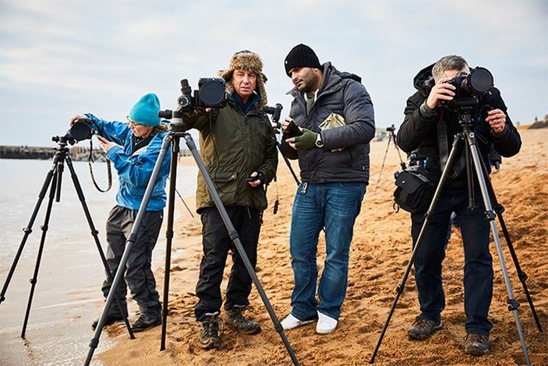 David and Sanjay discuss a shot behind a tripod on the beach, while Helen and Eddie shoot on either side.