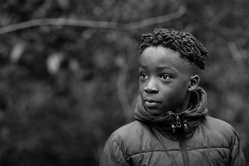 A portrait of young boy wearing a puffa jacket looking away from the camera.