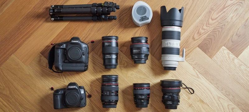 Canon cameras and lenses are laid out on a wooden surface.
