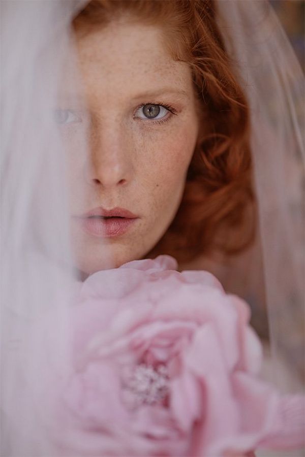 A close-up of a bride wearing a veil and holding pink flowers. Photo by Flicia Sisco with a Canon RF 85mm F1.2L USM lens.