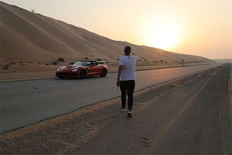 DOP Brett Danton walks towards the orange supercar in the desert at sunset.