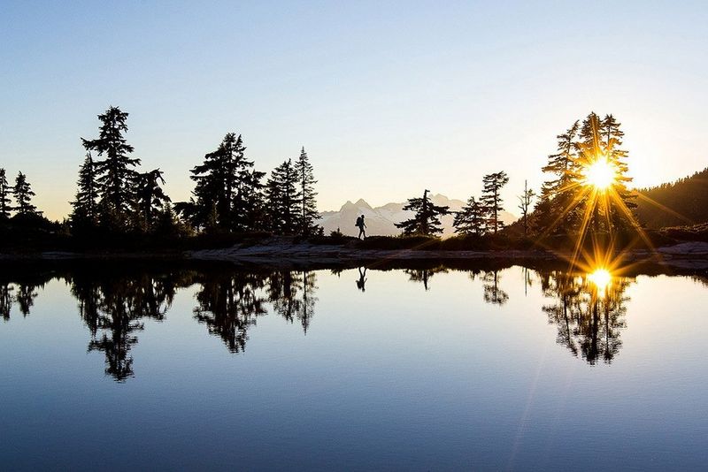 Inside a glacier, in a gap between two walls of ice, a man lies in a red hammock.