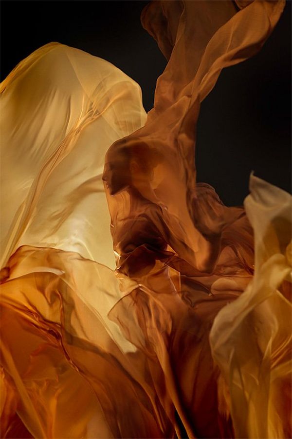 A ballet dancer is just discernible within billowing orange and yellow silks.