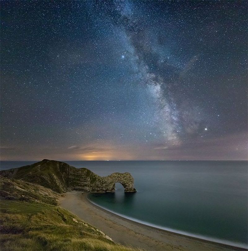 The Milky Way over a coastal arch.