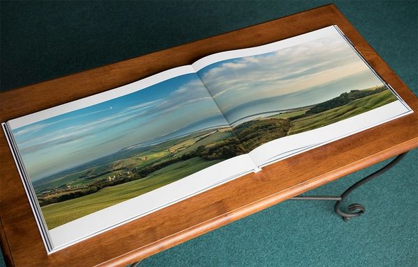 A double-page spread from David Noton's photobook Home Patch showing a panoramic coastal shot across both pages. 