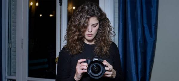 Photographer Carolina Arantes looks at her Canon camera.