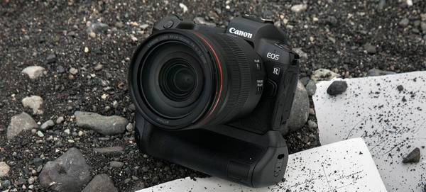 The Canon EOS R sits on a pile of black stones, some dirty paper underneath it