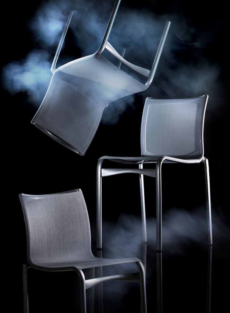 Three chairs, one seemingly suspended upside down, against a black background and with smoke effects. Photo by Eberhard Schuy