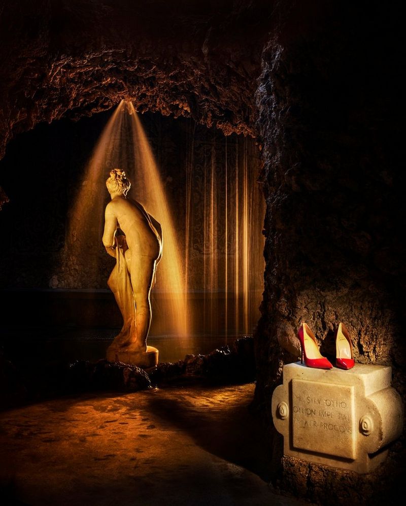 A statue of a woman, with red shoes in the foreground. Photo by Eberhard Schuy